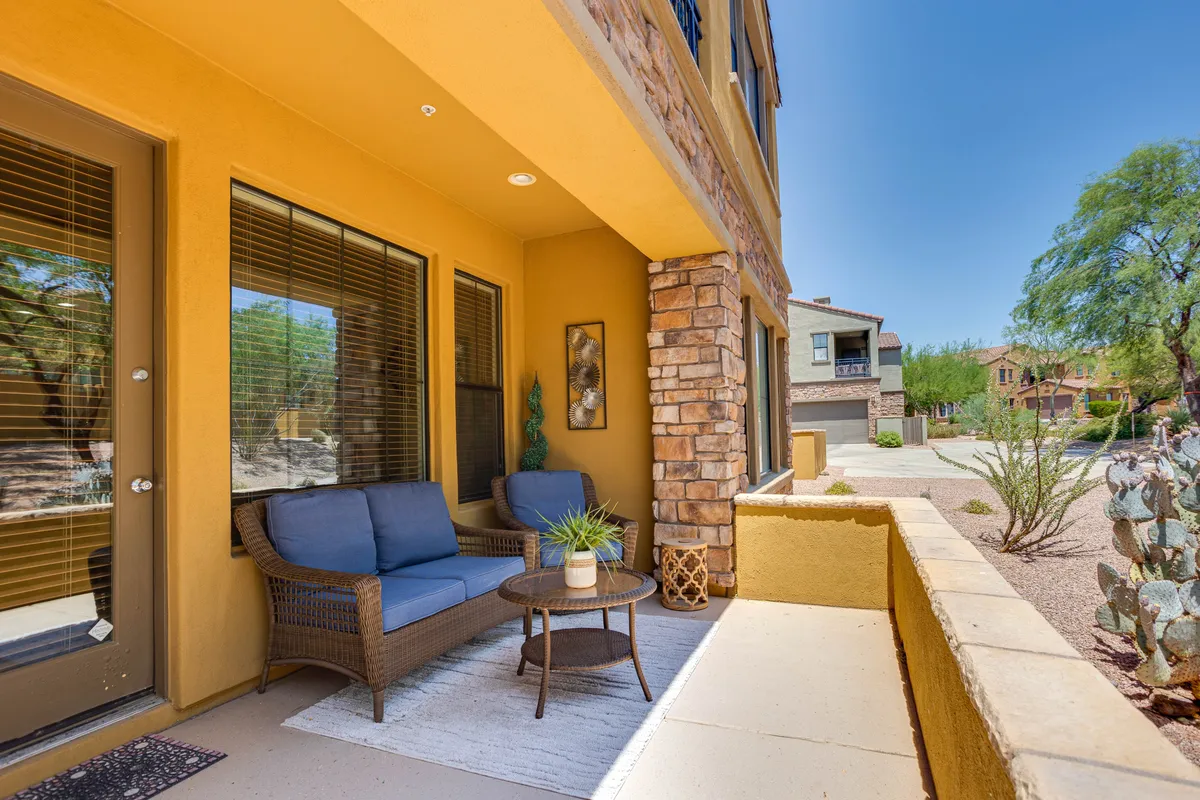 The private patio features comfortable outdoor seating, a decorative stone wall, and lush potted plants. The setting is ideal for soaking up sunny afternoons or enjoying intimate evening conversations.