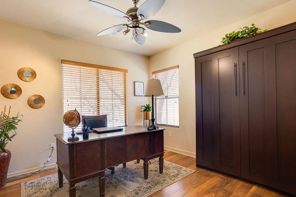 A serene, dedicated home office setup with a wooden desk, large storage cabinet, table lamp, and decorative wall mirrors. The calm, focused atmosphere makes it ideal for remote work or planning the day's adventures.