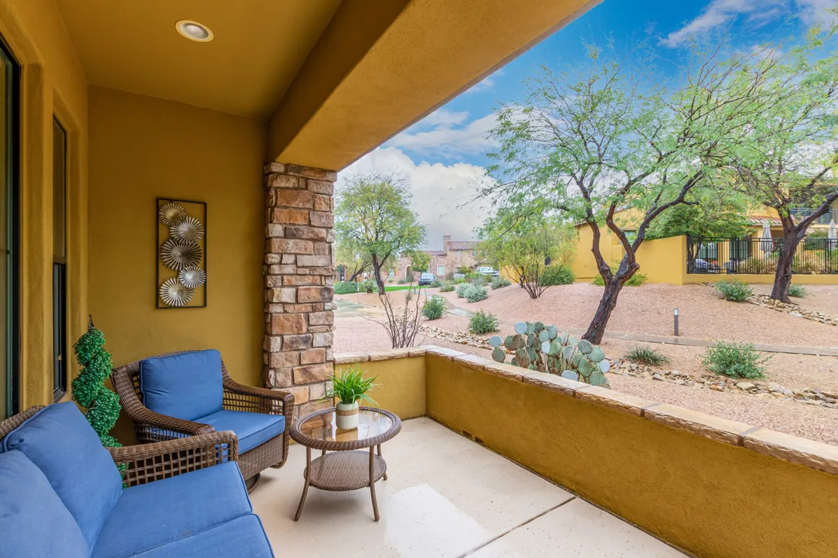 A tranquil patio area with blue seating, a round glass table, decorative wall art, and views of the landscaped surroundings. The setup encourages relaxation, casual conversations, and moments spent enjoying nature.