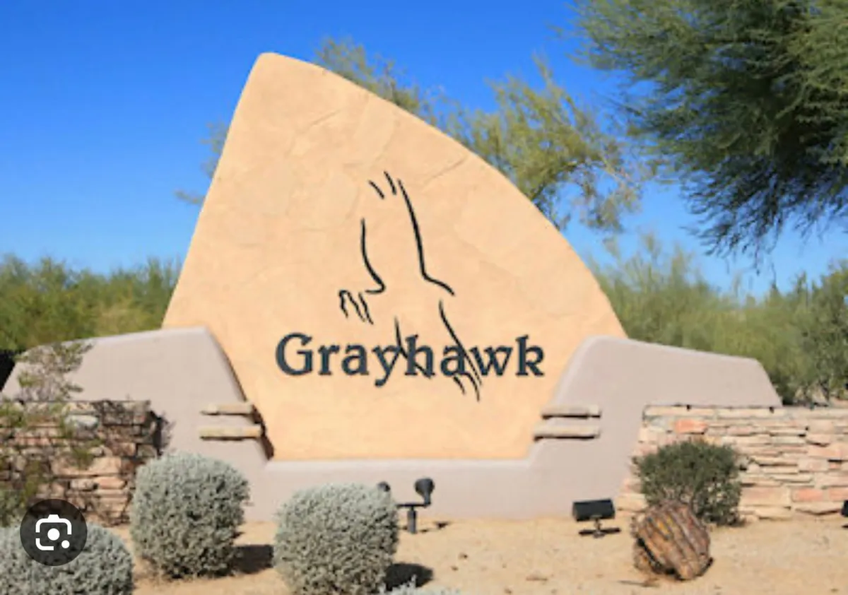 The welcoming Grayhawk community sign set amidst impressive desert landscaping and rugged rock formations. The entrance radiates a sense of arrival, exclusivity, and connection to the natural Arizona landscape.