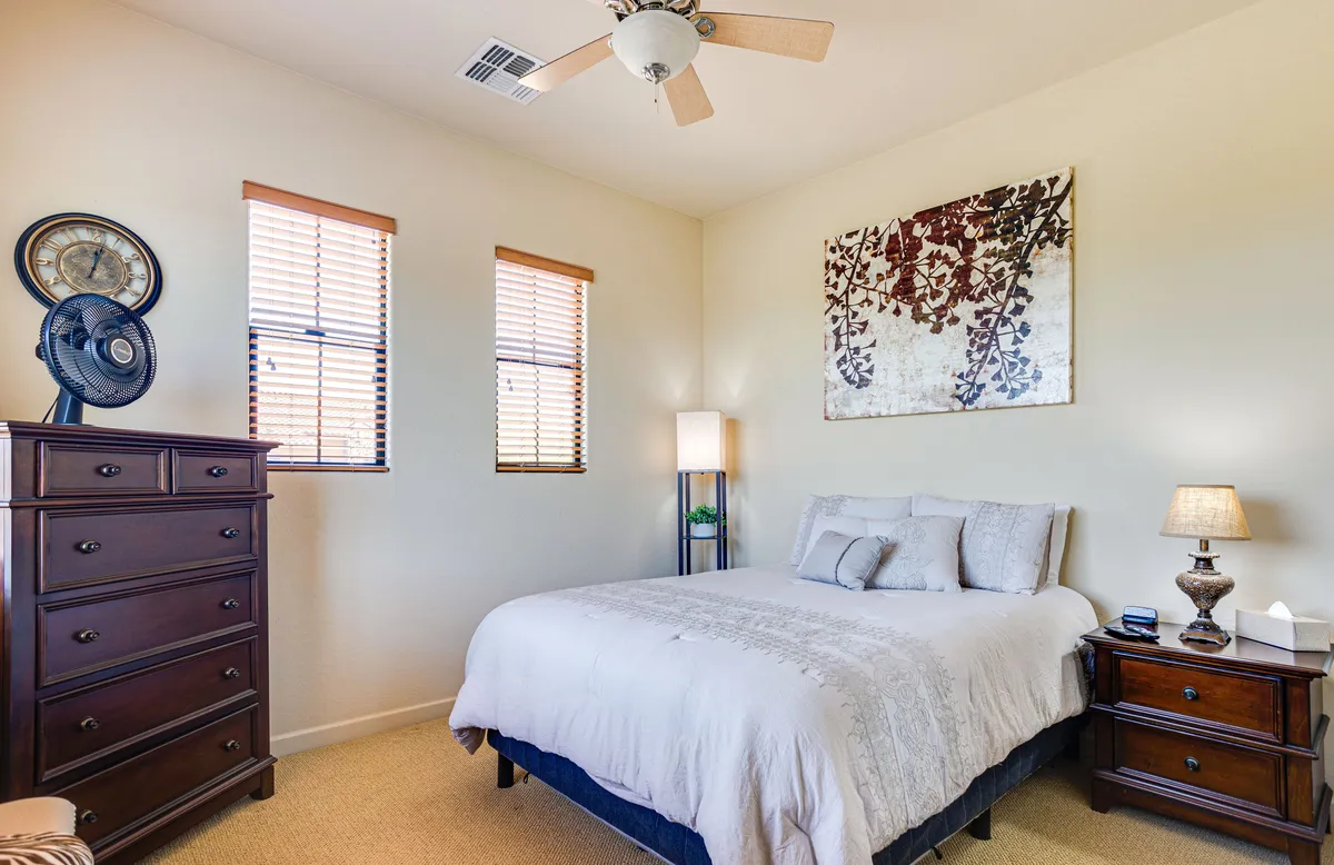A peaceful guest bedroom with a bed, nightstand, dresser, artwork, and windows that let in ample natural light. The room feels welcoming and restful, providing comfortable accommodations for guests.