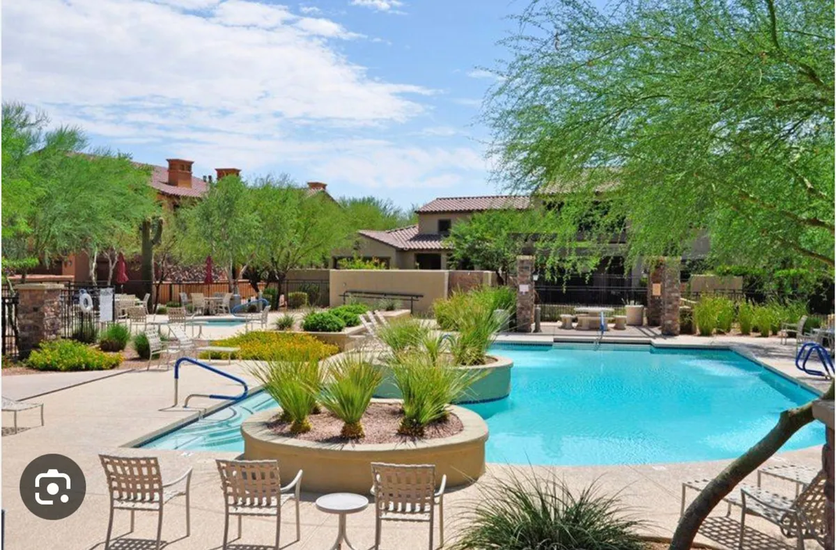 A sparkling swimming pool surrounded by lush greenery, comfortable lounge chairs, and tranquil water features. The setting suggests both relaxation and opportunities for social gatherings, especially during the sunset hours.