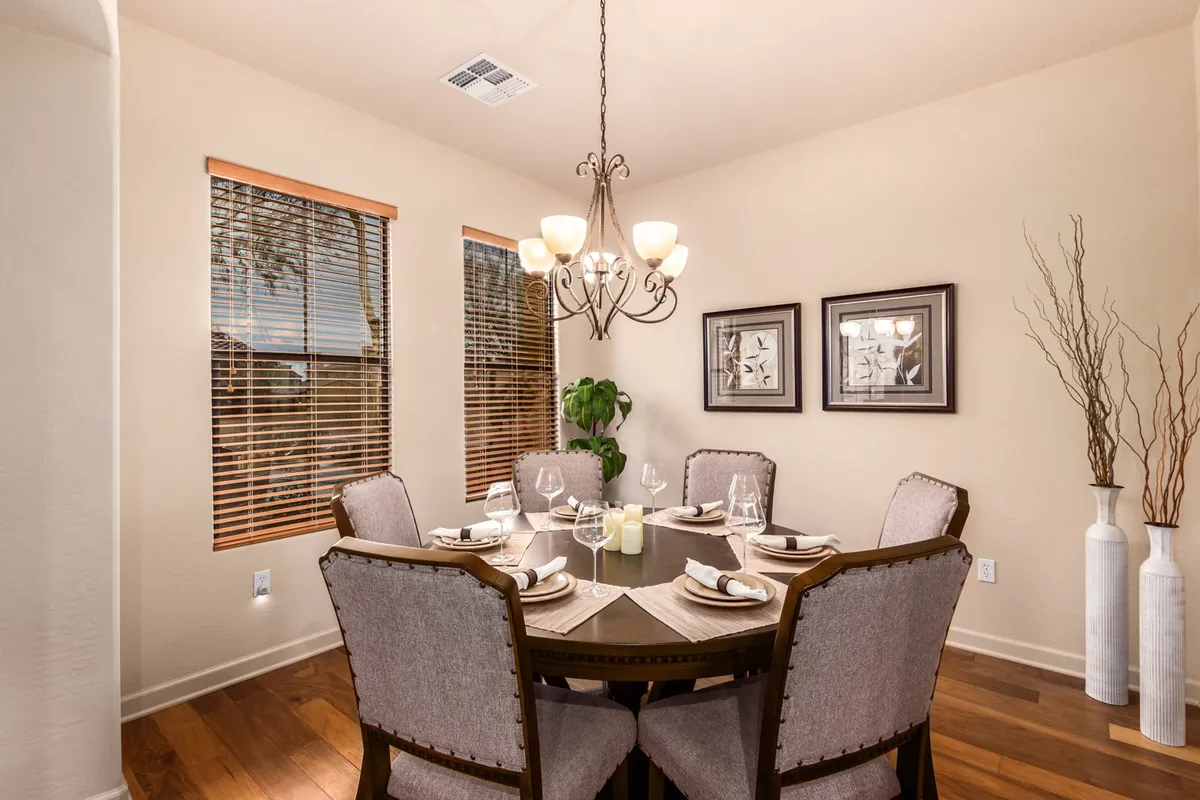 A warm, inviting dining area featuring a round table, elegant chandelier, comfortable dining chairs, and tasteful wall art. Decorative vases add a touch of sophistication, and the overall scene exudes a sense of togetherness for both formal dinners and casual breakfasts.