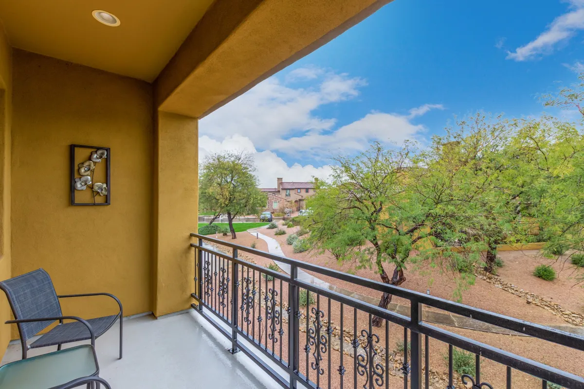 A tranquil private balcony with a decorative railing overlooks a scenic landscape. The space is adorned with tasteful wall art and is bathed in soft natural light, creating an inviting setting for relaxation, morning coffee, or evening drinks.